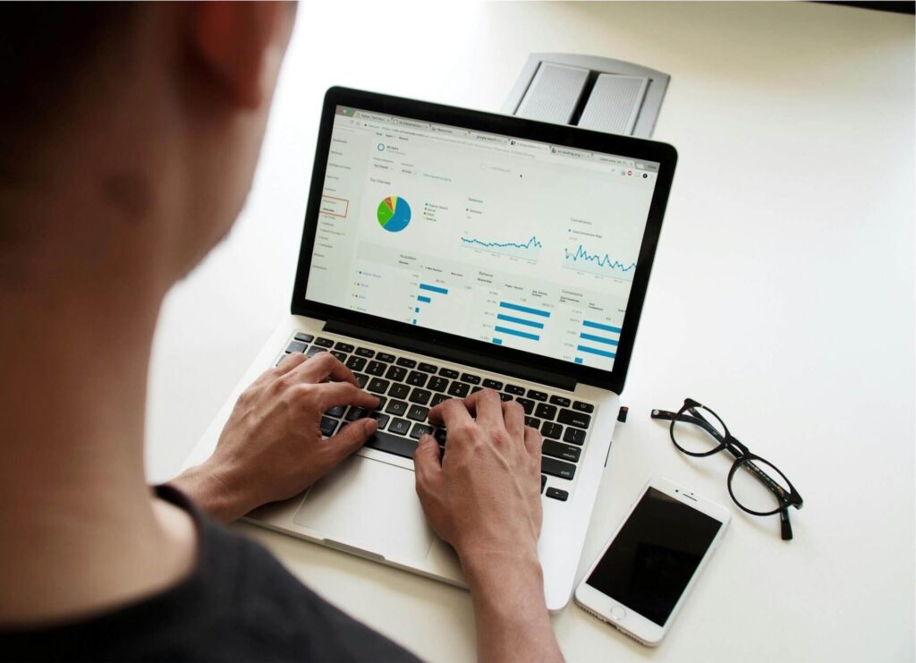  Un profesional trabajando en su portátil analizando gráficos, métricas y paneles de un software de organización digital.
